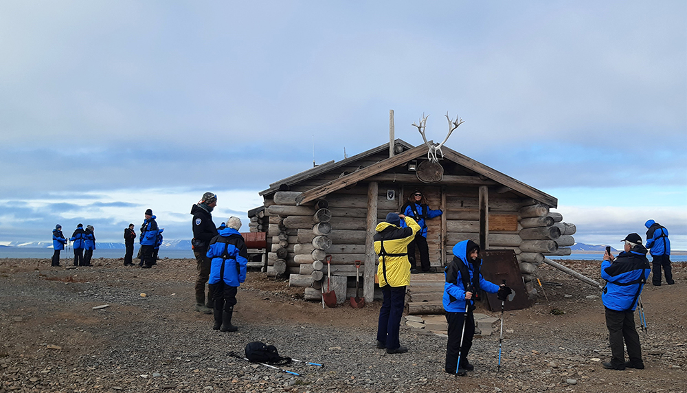 Turister foran fangsthytte på Svalbard